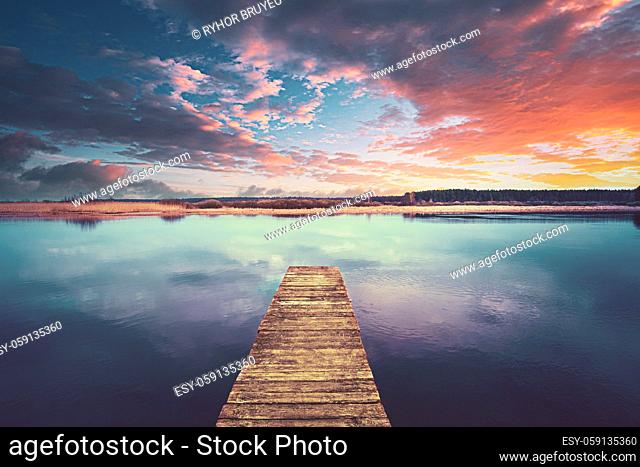 Colorful Sunset Sunrise Dramatic Sky Above Wooden Boards Pier On Calm Water Of Lake, River. Nature, Peace Concept