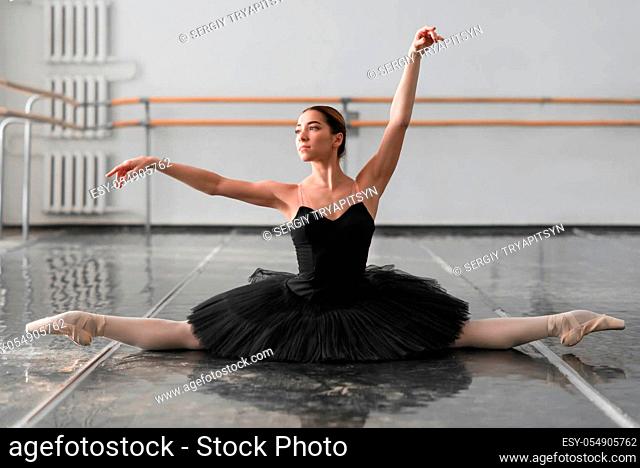 Beautiful ballerina sit on the twine in class. Legs stretching exercise