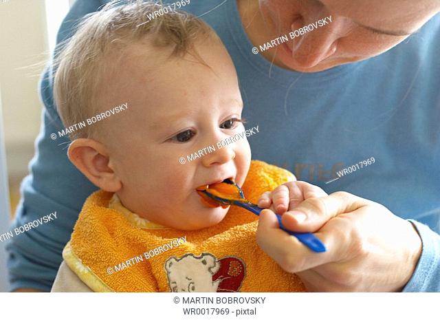 baby feeded with carrot mash by mother