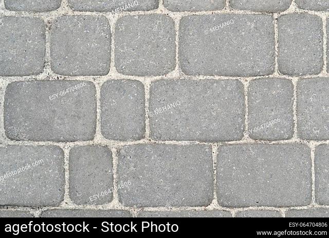 Fragment of the road, laid out of paving stones. Several rectangular stones of cement with smooth corners