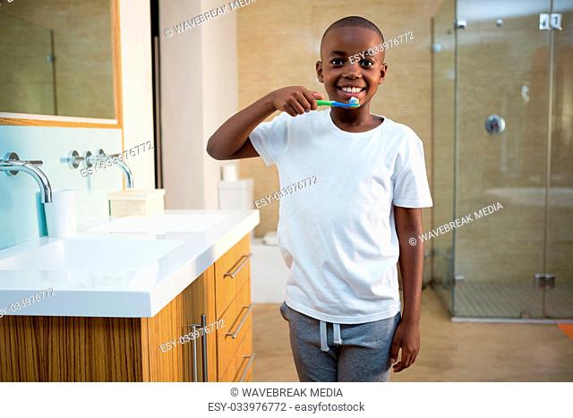 Portrait of smiling boy with toothbrush by sink