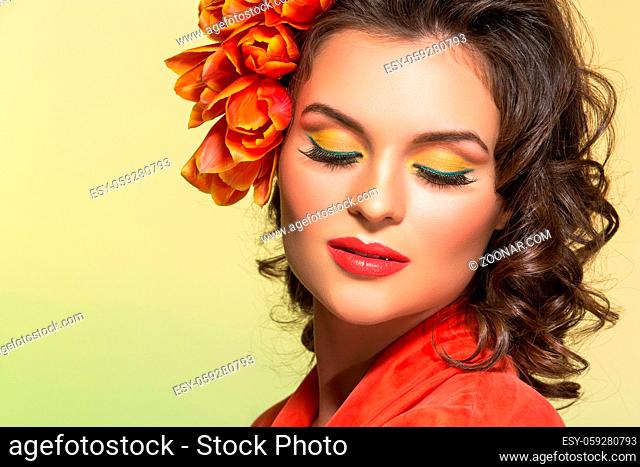 beautiful young woman in orange dress with flowers in hair. closeup studio shot on yellow background. Copy space