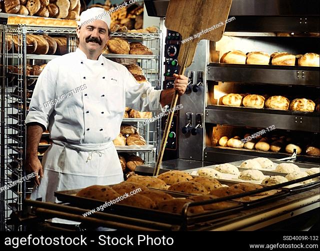 Portrait of a baker standing in a kitchen with breads