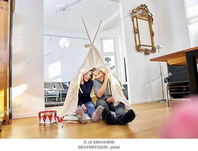 Smiling couple sitting on floor in a teepee