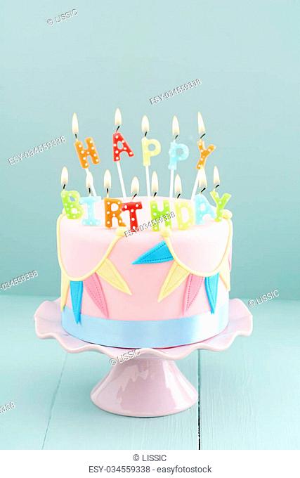 Fondant covered pastels coloured birthday cake with happy birthday candles