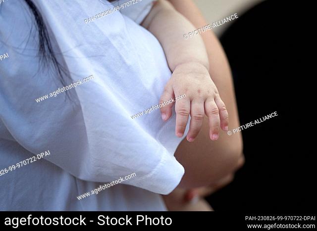 SYMBOL - 10 July 2023, Berlin: A mother holds her sleeping baby in her arms. Photo: Fernando Gutierrez-Juarez/dpa. - Berlin/Berlin/Germany