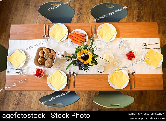 16 August 2021, Hamburg: A laid table with rolls, carrots, tomatoes and various spreads before a joint breakfast after the distribution of organic bread boxes...
