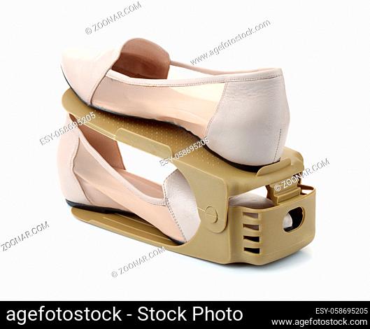 Pair of shoes on plastic storage shoes rack holder isolated on white