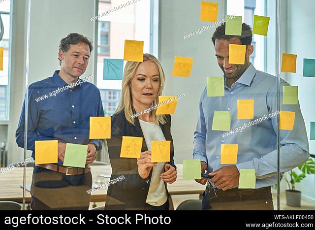 Business professionals planning strategy on adhesive notes in board room at office