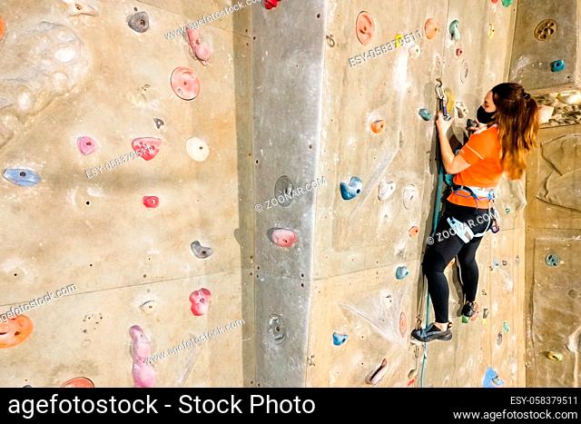 Young fit woman climbing on indoor rock wall. Aerial cinematic footage . High quality photo