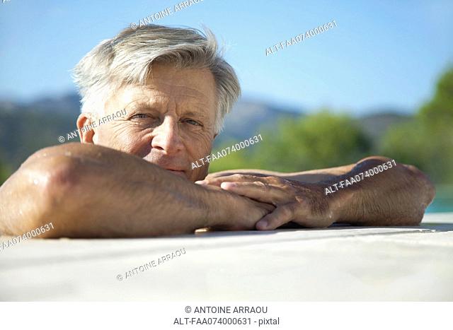 Senior man relaxing at poolside, portrait