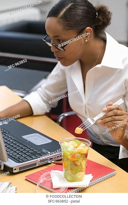 Woman eating fruit salad in the office