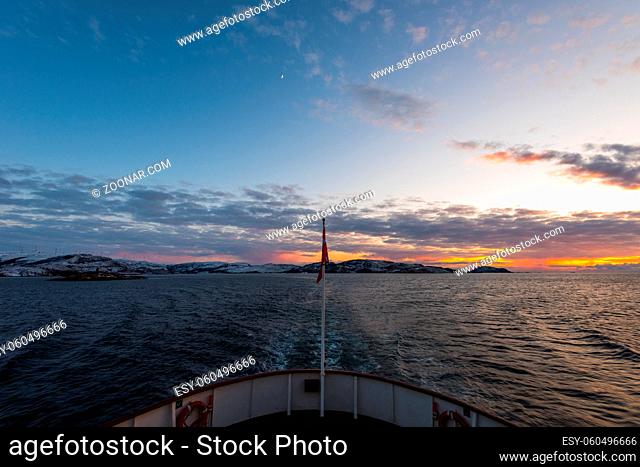 Amazing colorful sunset over Norwegian sea seen from small cruise ship MS Lofoten of Hurtigruten on clear winter day