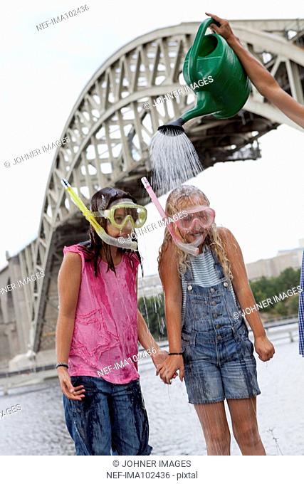 Girls wearing diving masks under watering can