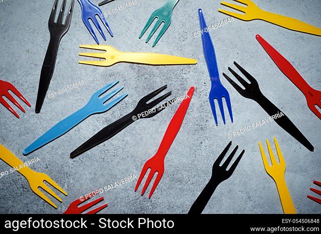 Multicolored plastic cutlery on a stone table