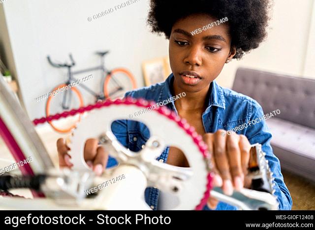 Afro hairstyle woman repairing bicycle chain at home