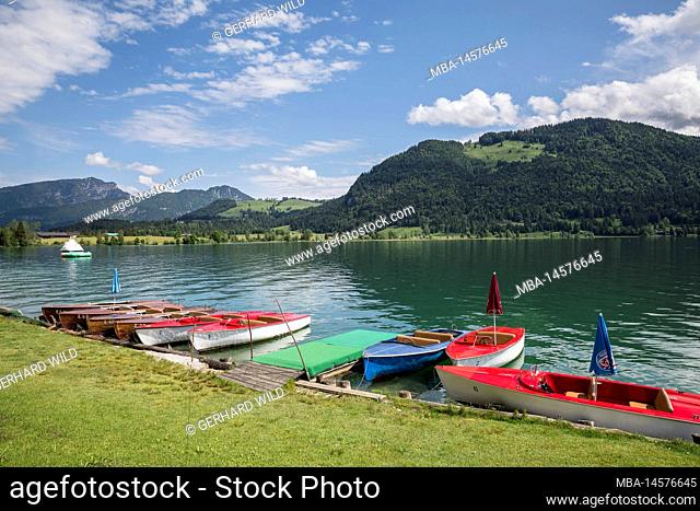 Boats on the shore of Walchsee, behind the Kaisergebirge with Ebersberg (1164 m) on the right, Walchsee, Kaiserwinkl, district Kufstein, Tyrol, Austria