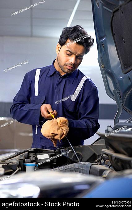 A mechanic checking motor oil during the maintaince and servicing of a car