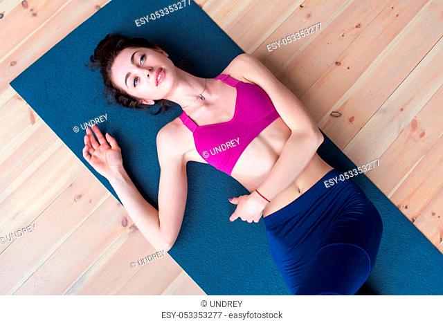 Pretty smiling Caucasian girl lying on floor relaxing at the end of yoga class