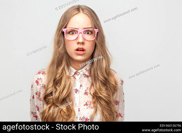 Fear concept. Teenager girl, looking at camera, with surprised face. Studio shot, isolated on gray background