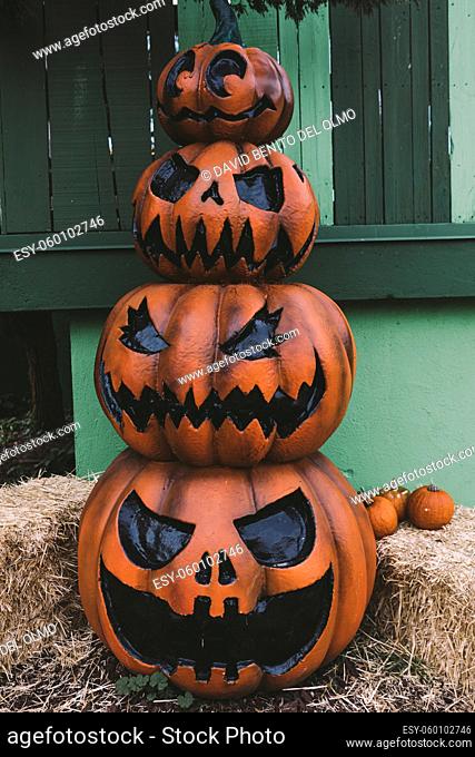 Three decorative Halloween Jack-o-Lantern pumpkins, one on top of the other, on the street. Halloween and carnival celebration concept