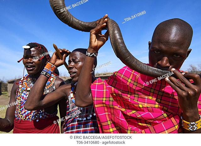 A Masai man blows an Ikudu horn and play music for tradionnal dancing. Masai Mara National Reserve, Kenya