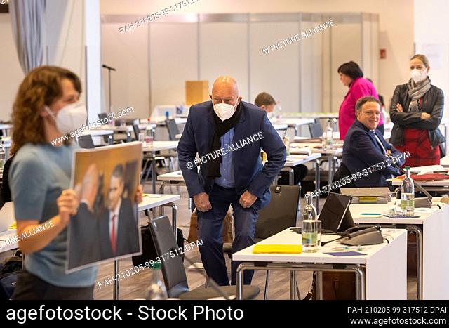 05 February 2021, Thuringia, Erfurt: Thomas Kemmerich (FDP, M) watches as members of the SPD, Bündnis90/Die Grünen and Die Linke factions admonishly hold up a...