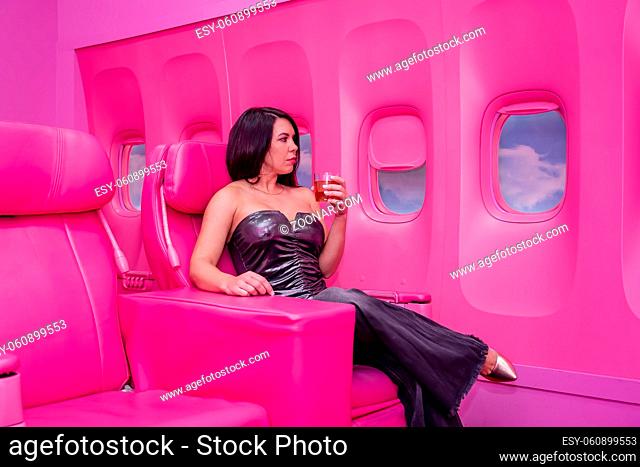 A beautiful asian model sits in a pink airplane ready for her next adventure