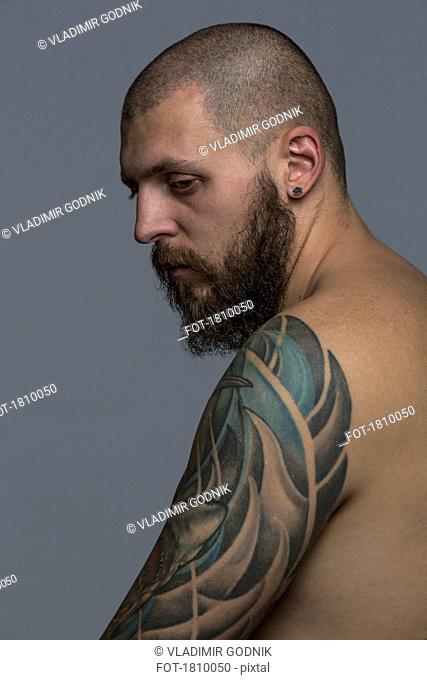 Portrait serious man with beard and tattooed arm