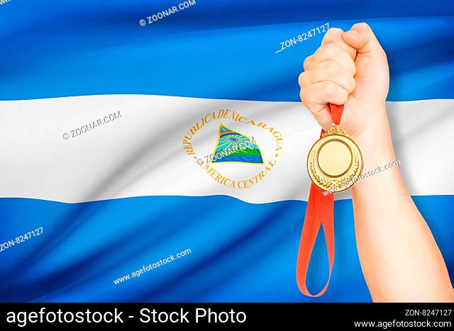 Sportsman holding gold medal with flag on background - Republic of Nicaragua