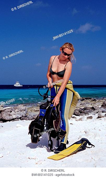 Woman preparing to dive on the beach, Netherlands Antilles, Bonaire, Caribbean Sea