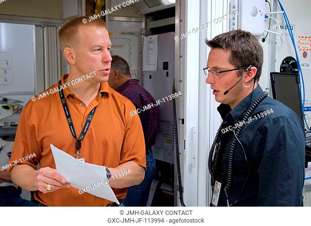 Astronaut Tim Kopra (left), STS-127 mission specialist, discusses training activities with United Space Alliance instructor Landon Lagasse in the Jake Garn...
