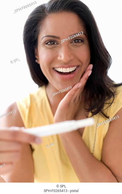 Happy woman looking at pregnancy test