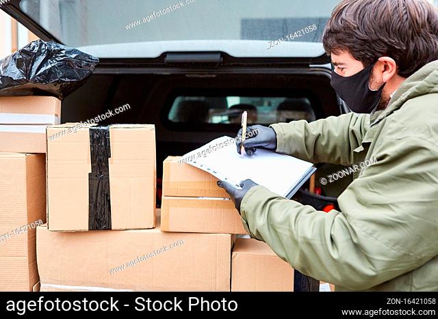 Paketbote mit vielen Paketen im Kofferraum vom Lieferwagen mit Gesichtsmaske wegen Covid-19