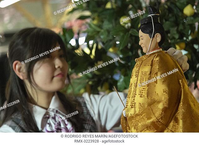 An employee looks at a Japanese 'hina' doll modeled after Crown Prince Naruhito at Kyugetsu Company's showroom. This year