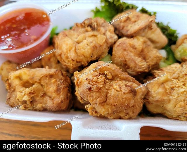 Vietnamese fried tofu chunks with dipping sauce in container
