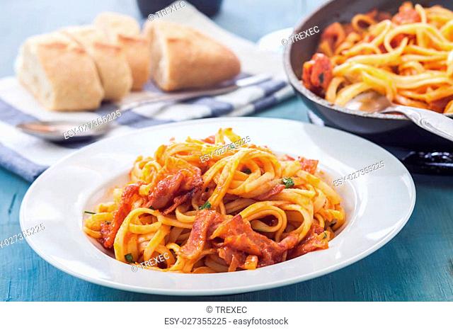 amariciana style fetuccini with bacon and tomato sauce on white bowl