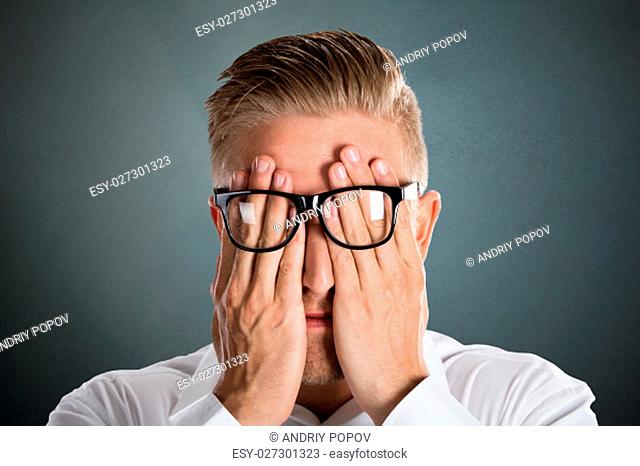Man's Hand Over The Face With Eyeglasses Over Grey Background
