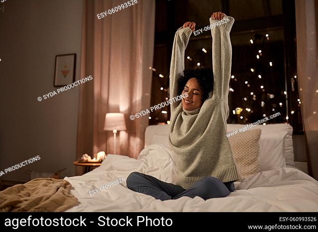woman in sweater stretching in bed at night