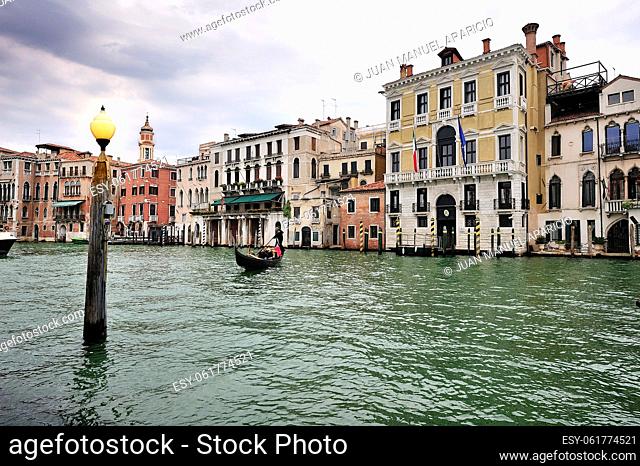 Grand Canal photographed with a gradient filter on a gray day, we can see a wooden pole in the foreground emerging from the water with a lighted lamp on top and...