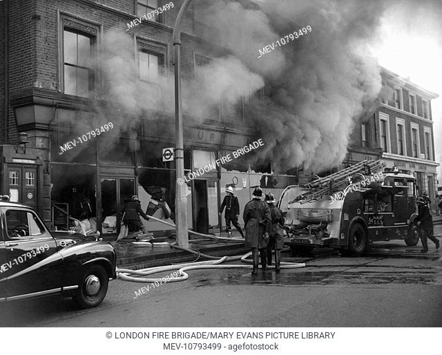 London firefighters and the London Salvage Corps (in the long coats) at the scene of a fire involving shops and dwellings in Wandsworth Road, Clapham, SW8