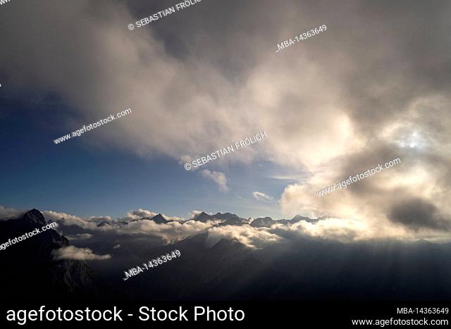 Light mood over the Karwendel with clouds and sunbeams, view from the Fleischbank to the Falkengruppe. The mountain peaks peek out slightly from the clouds