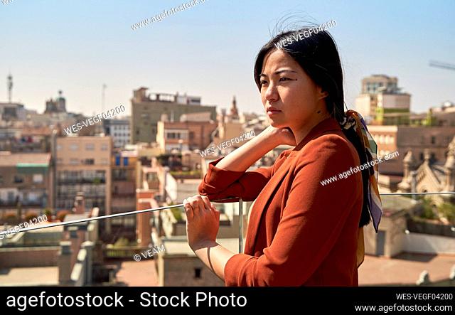 Thoughtful woman looking at view while standing on building terrace