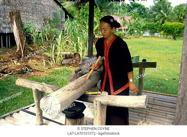 Sarawak Cultural Village. Woman preparing to crush, press sugar cane for juice