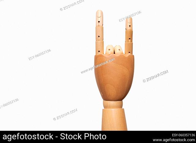Right hand of wooden dummy mannequin showing sign of the horns into camera on white background
