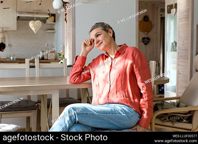 Daydreaming woman sitting at wooden table at home