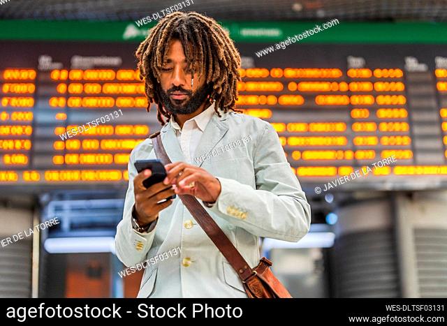 Businessman using mobile phone at central station