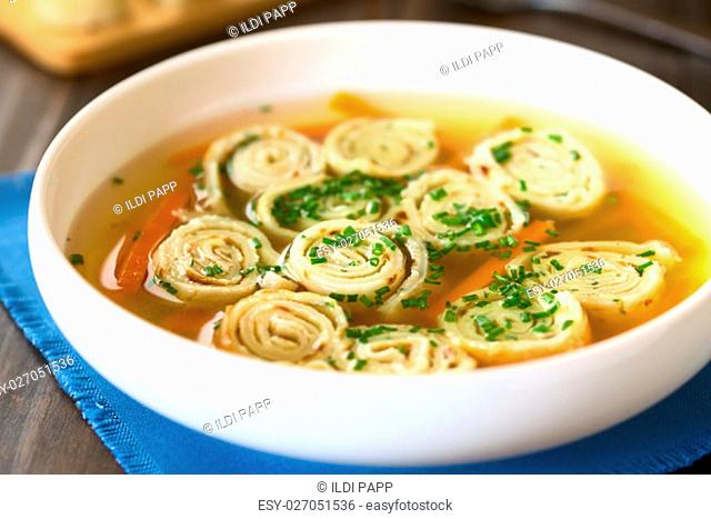 Traditional German Flaedlesuppe and Austrian Frittatensuppe based on consomme with rolls or stripes of pancake or crepe garnished with chives