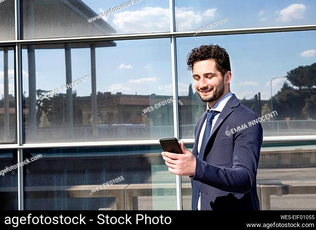 Male professional using mobile phone while standing in front of building