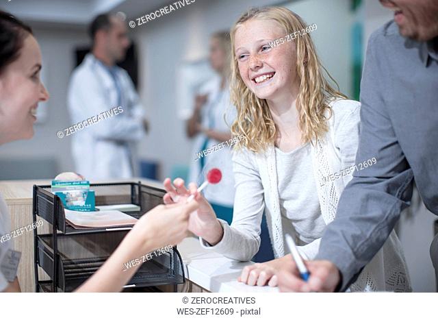 Sick girl getting lollipop from receptionist in hosptal